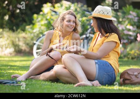 amici felici che parlano e ridono seduti in un parco Foto Stock