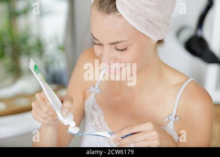 donna che stringe il dentifricio sullo spazzolino in bagno Foto Stock