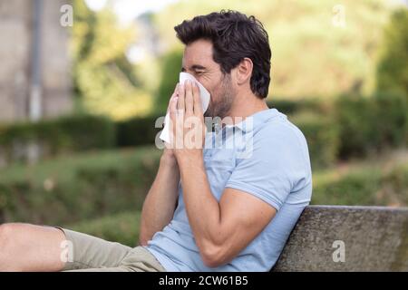 uomo che soffia naso su tessuto contro scena autunnale in foresta Foto Stock