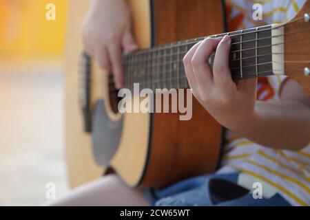 Ragazza addestrata a suonare la chitarra acustica, pratica la chitarra Foto Stock