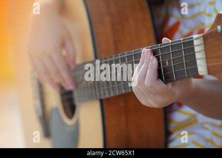 Ragazza addestrata a suonare la chitarra acustica, pratica la chitarra Foto Stock