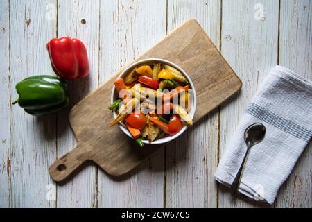 Verdure fresche fatte in casa e carne saltati in una ciotola su un piatto di legno Foto Stock