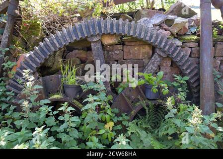 Grandi ingranaggi e ruote di mulino arrugginiscono in sottobosco su Una fattoria in Cumbria Foto Stock