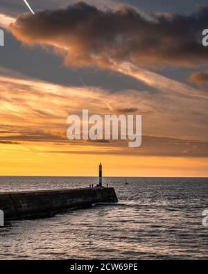 Tramonto ad Aberystwyth sulla costa gallese mentre la gente pesca nell'ultima luce del giorno. Foto Stock