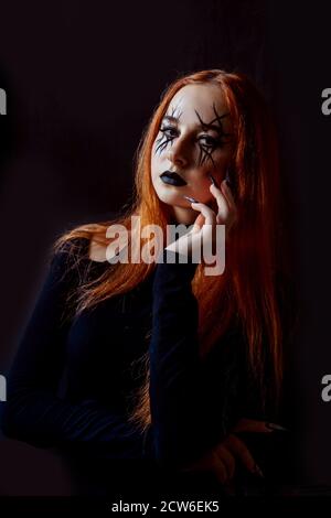 Halloween zenzero donna strega con lunghi chiodi spaventosi e moda Halloween compongono. Sfondo nero. Foto Stock