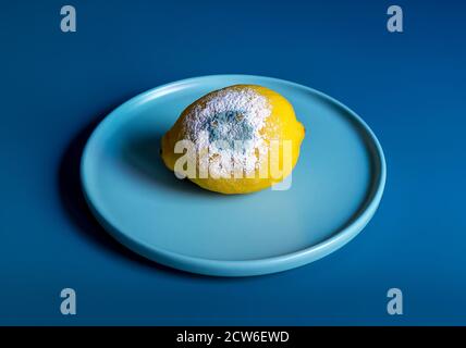 Limone guastato giallo con muffa su sfondo blu Foto Stock