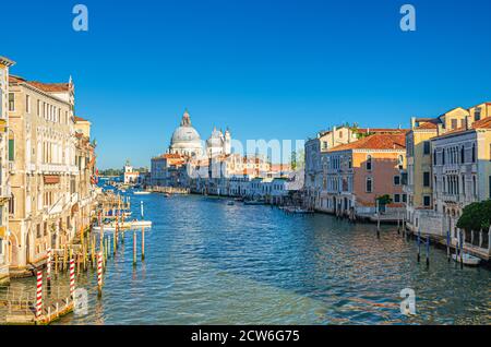 Il paesaggio urbano di Venezia con il Canal Grande nel centro storico della città. Chiesa cattolica di Santa Maria della Salute su Punta della Dogana, sfondo blu cielo. Veneto, Italia. Foto Stock