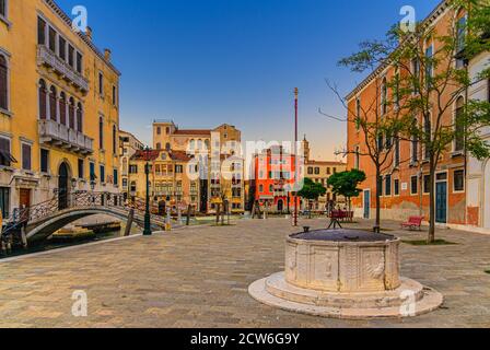 Campo San Vio con Palazzo Cini e Palazzo Barbarigo palazzi, pozzo in pietra e ponte attraverso lo stretto canale d'acqua, edifici sul Canal Grande nel centro storico di Venezia background, Italia Foto Stock