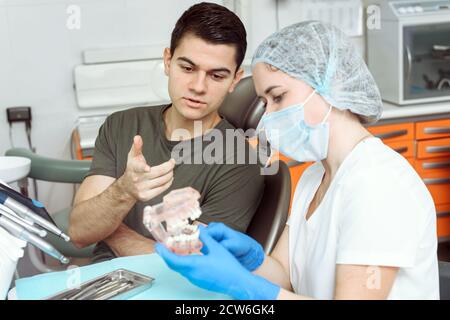 Il dentista racconta al paziente il trattamento imminente. Il concetto di trattamento dentale e di andare alla clinica dentale. Foto Stock