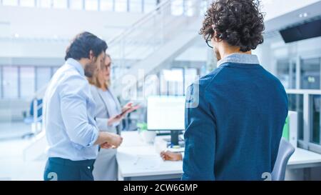 Nel gruppo di ufficio occupato luminoso sopra il colpo della spalla del giovane uomo d'affari professionale che cammina al suo posto di lavoro. Foto Stock