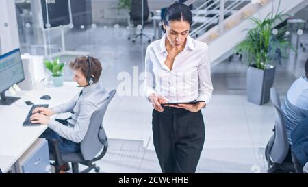 Beautiful Female Manager è Walking Pass i suoi colleghi del Customer Service Operator e supervisiona il loro lavoro. Persone diverse e motivate del call center Foto Stock