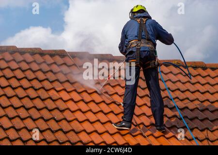 operatore che lava il tetto con acqua pressurizzata Foto Stock