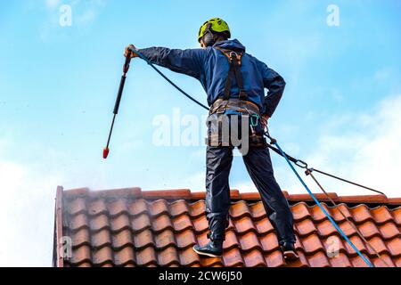 operatore che lava il tetto con acqua pressurizzata Foto Stock