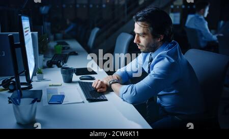 Nell'ufficio di notte ha sovraccaricato il lavoro stanco dell'ufficio usa il computer desktop. Stanco esausto uomo d'affari quasi cade addormentato al suo lavoro Foto Stock