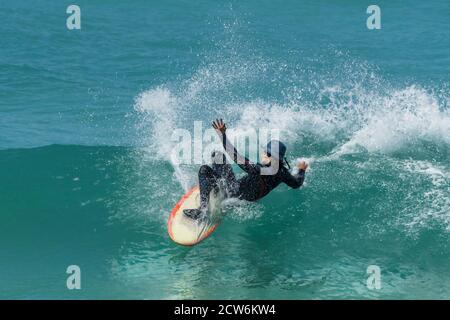 Azione spettacolare come un surfista si svanisce mentre cavalca un'onda a Fistral a Newquay in Cornovaglia. Foto Stock