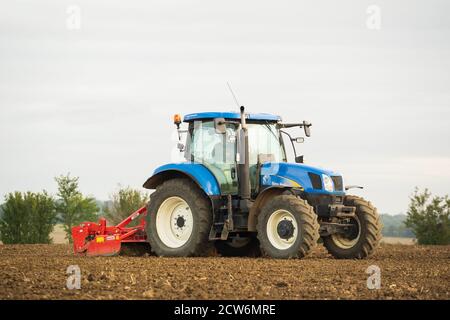 Coltivatore che utilizza un trattore in un campo che prepara il terreno per la semina e la semina in autunno. Molto Hadham, Hertfordshire. REGNO UNITO Foto Stock