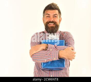 Concetto di regalo a sorpresa e per le vacanze. Macho con confezione regalo blu e arco bianco. Ragazzo in camicia plaid abbracci presente scatola. Uomo con barba e viso allegro isolato su sfondo bianco. Foto Stock