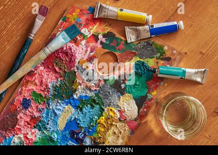 Tavolozza colorata con pennelli e colori ad olio su un tavolo in legno d'epoca. Foto Stock