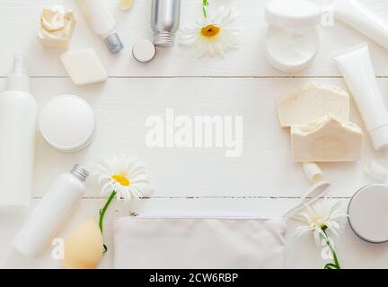 Set cosmetici bianco CORNICE su tavolo di legno con fiori. Bellezza cura della pelle trattamento dei capelli siero cosmetico olio idratante crema per la pelle burro corpo Foto Stock