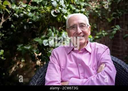 Ritratto di sorridente uomo anziano che si rilassa in giardino a casa Foto Stock