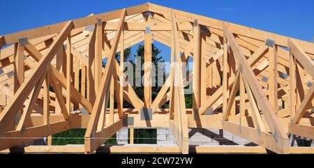 Costruzione di case con struttura in legno con travi a vista, travi a capretto, legname, bretelle e navate di una casa in mattoni contro il cielo blu e f Foto Stock