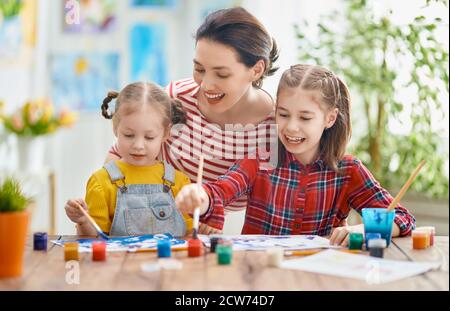 Buona famiglia. Madre e figlie che dipingono insieme. Donna adulta che aiuta la bambina. Foto Stock