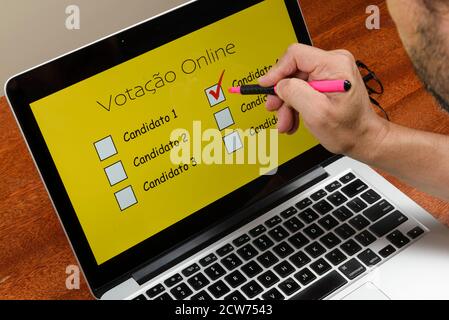 Persona che vota sul computer tramite Internet con Testo votazione online in portoghese Foto Stock