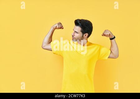 Bell'uomo muscoloso mostra i muscoli sulle braccia su sfondo giallo. Concetto di potenza Foto Stock