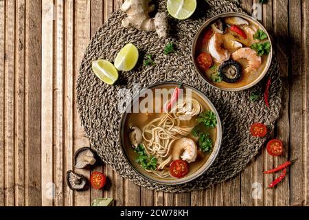 Varietà di zuppe asiatiche. Tradizionale zuppa di zuppa di zuppa di zuppa di zuppa di zuppa di zuppa di tom yum e spiccate con funghi shiitake, gamberi, ingredienti sopra su tovagliolo di paglia Foto Stock