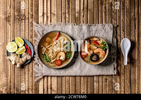 Varietà di zuppe asiatiche. Tradizionale zuppa di zuppa di zuppa di zuppa di zuppa di zuppa di tom yum e pasta con funghi shiitake, gamberi, ingredienti sopra su panno di lino su WO Foto Stock