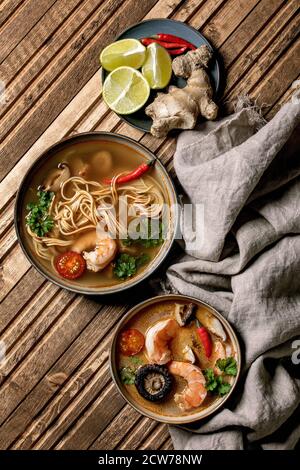 Varietà di zuppe asiatiche. Tradizionale zuppa di zuppa di zuppa di zuppa di zuppa di zuppa di tom yum e pasta con funghi shiitake, gamberi, ingredienti sopra su panno di lino su WO Foto Stock