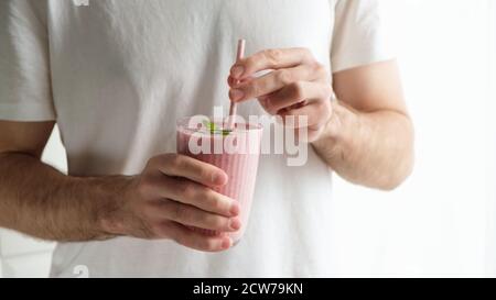 Calzare l'uomo che tiene il frullato rosa delle bacche nelle mani Foto Stock