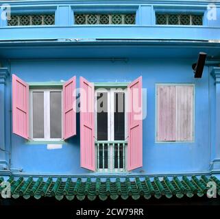 Un negozio blu restaurato peranakan con persiane rosa in legno. Foto Stock