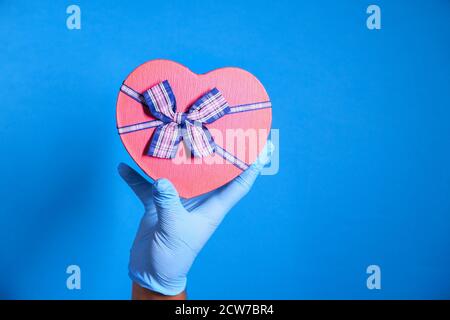 la mano maschile in un guanto medico blu dà un regalo. Foto Stock
