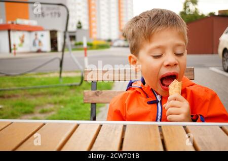 POZNAN, POLONIA - 08 settembre 2020: Piccolo ragazzo caucasico polacco di tre anni che mangia gelato da un tavolo di legno. Foto Stock