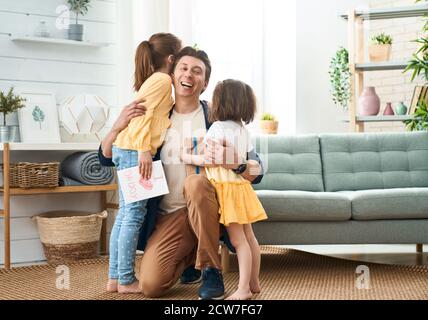 Buon giorno del padre! Figlie di bambini che si congratulano con papà e gli danno una scatola regalo. Papà e ragazze sorridenti e abbraccianti. Vacanze in famiglia e togethernes Foto Stock