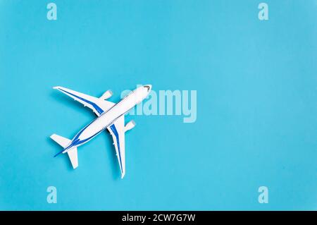 Aeroplano bianco su sfondo blu con spazio di copia per il testo. Concetto di viaggio minimo. Composizione in stile piatto per agenzia di viaggio o compagnia aerea Foto Stock