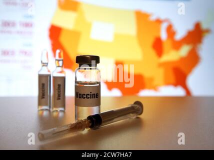 In questa illustrazione fotografica, flaconcini di falso 'vaccino Covid-19' e una siringa visto visualizzati con una COVID-19 coronavirus statistiche in background. Foto Stock