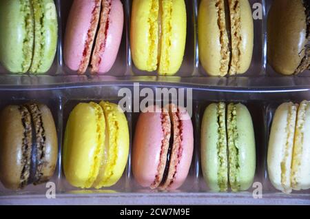 Macaroni colorati e gustosi in fila. Macaroni di colori diversi su sfondo marrone Foto Stock