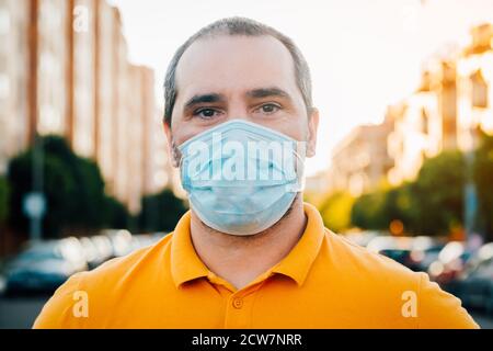 Primo piano ritratto di 40s uomo in una maschera facciale usa e getta. Foto Stock