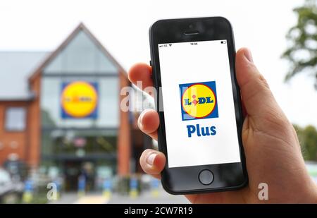 Un uomo che usa l'app Lidl Plus sul suo telefono Al di fuori di un negozio Lidi nel Regno Unito Foto Stock