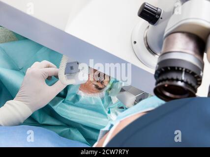 Donna con occhio aperto in ospedale sotto il microscopio Foto Stock