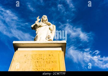 POZNAN, POLONIA - 20 settembre 2020: Scultura di Gesù con testo inciso sotto un cielo blu. Foto Stock