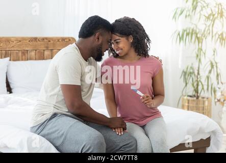 Felice coppia nera avendo grandi notizie, tenendo positivo test di gravidanza Foto Stock