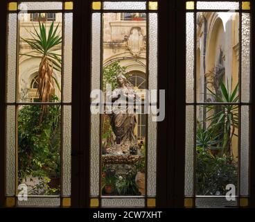 Un cortile interno della Chiesa di San Francesco d'Assisi a la Valletta, Malta è raffigurato attraverso le finestre con vetrate colorate e piombo. Foto Stock