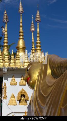 Testa dell'immagine dorata del Buddha reclinato e guglie dorate al tempio buddista di Wat Phong Sunan, Phrae, nel nord della Th Foto Stock