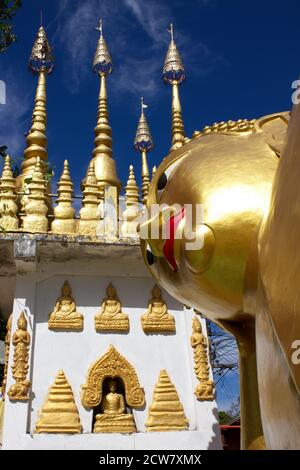 Testa dell'immagine dorata del Buddha reclinato e guglie dorate al tempio buddista di Wat Phong Sunan, Phrae, nel nord della Th Foto Stock