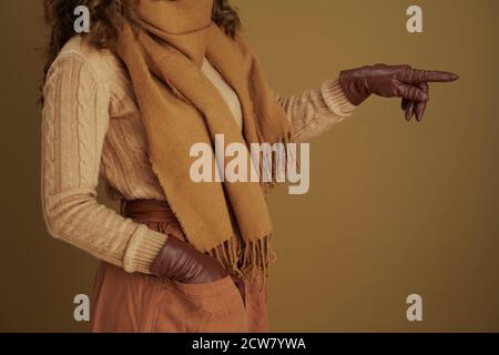 Ciao autunno. Primo piano su donna in sciarpa con guanti in pelle che puntano a qualcosa sullo sfondo beige. Foto Stock