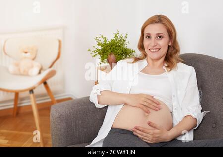 Donna incinta rilassante sul divano Foto Stock