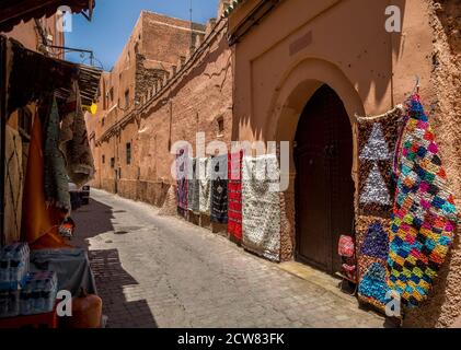 Tappeti in vendita appesi sulla strada. Tipico vicolo muraglia presso la Medina di Marrakech. Foto Stock